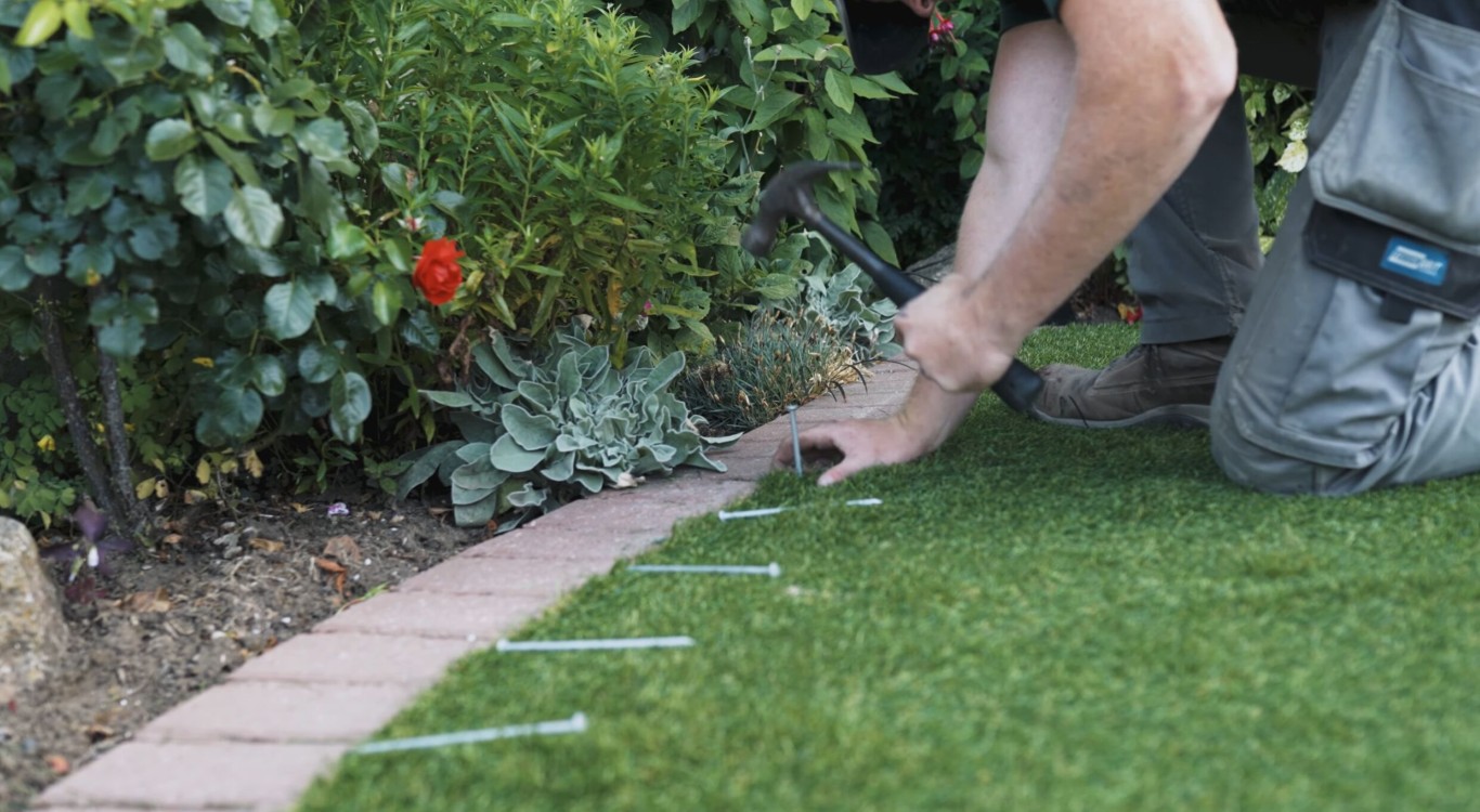 Professional installing artificial grass near garden bed in Richland, WA
